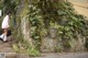 A woman walking down a sidewalk next to a stone wall.